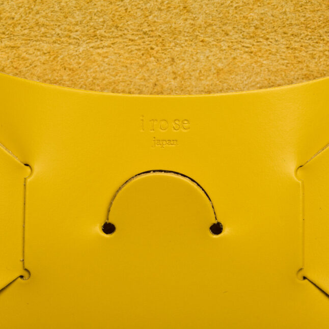 Detail of embossed irose company logo on yellow leather seamless card holder from Japan House London