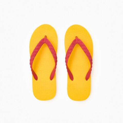Top view of a pair of yellow rubber flip-flops with red straps.