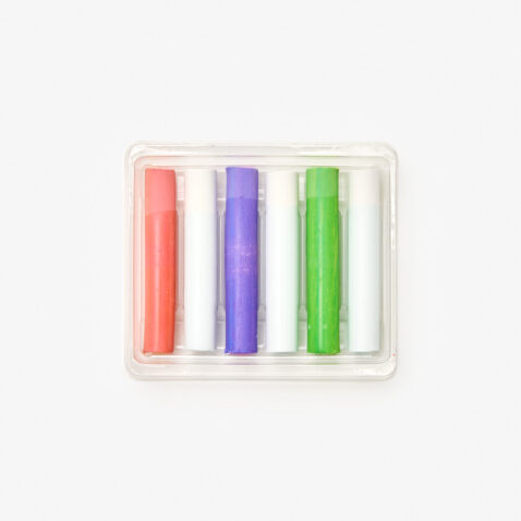 3 coloured and 3 white dustless chalks displayed in their box. The chalks are arranged in an alternating order from left to right, beginning with orange, white, purple, white, green and lastly white again.