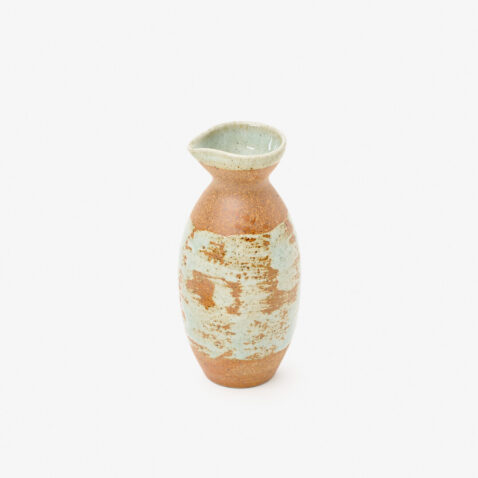 A Japanese porcelain sake bottle with a mix of mint blue and copper-red colours sitting on a white background