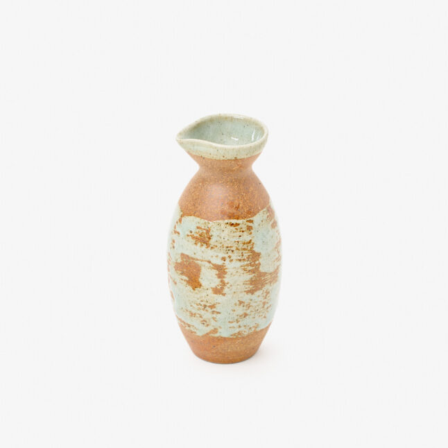 A Japanese porcelain sake bottle with a mix of mint blue and copper-red colours sitting on a white background