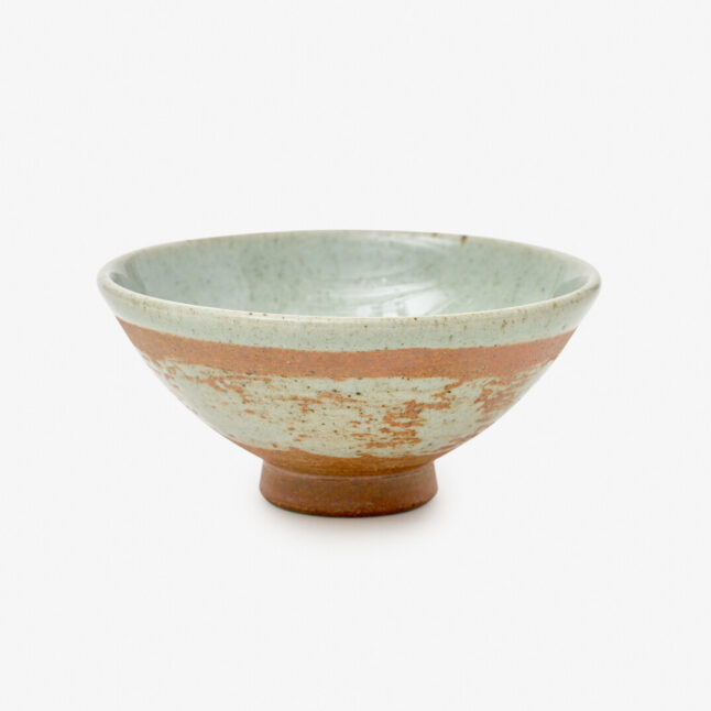 A rustic Japanese porcelain rice bowl with a mix of mint blue and copper-red colours sitting on a white background