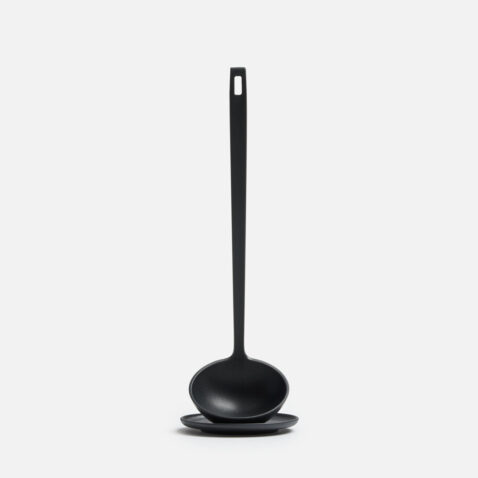 A black ladle sitting on top of a small black plate from the front