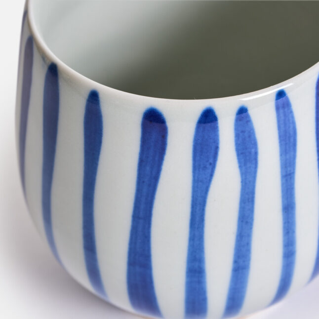 Striped pattern of a white base with gosu blue stripes on a rounded ceramic cup from Japan House London
