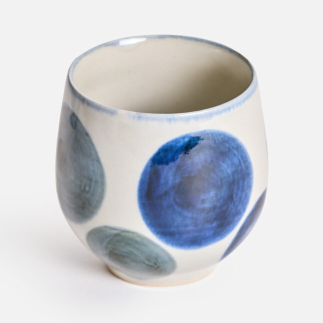 A rounded ceramic cup with a blue round pattern from Japan House London