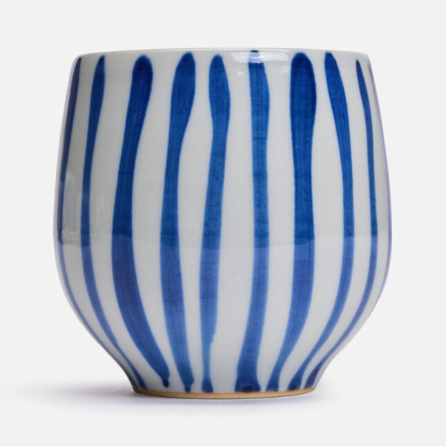 Striped pattern of a white base with gosu blue stripes on a rounded ceramic cup from Japan House London