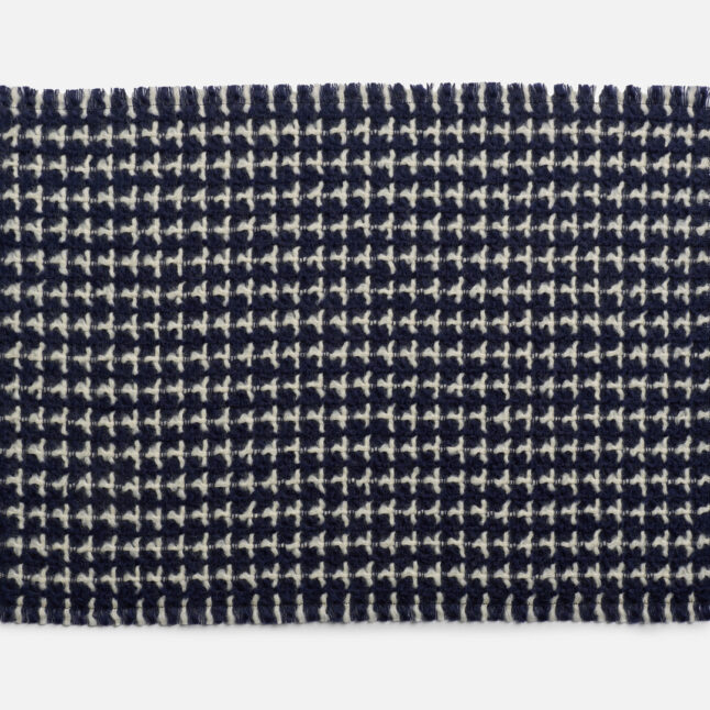 A wool table mat with a dark blue background and white check pattern from Japan House London.