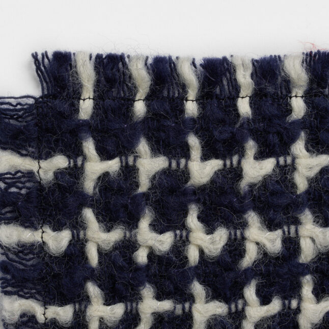 A wool table mat with a dark blue background and white check pattern from Japan House London.