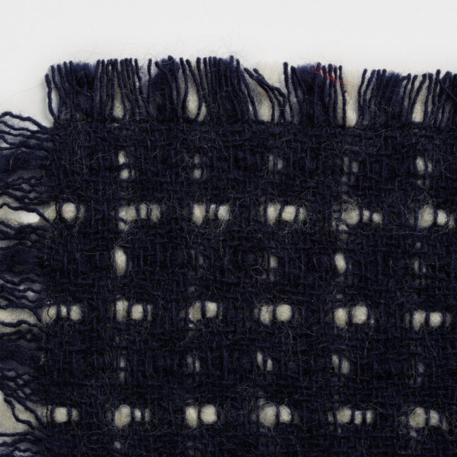 A wool table mat with a dark blue background and white check pattern from Japan House London.