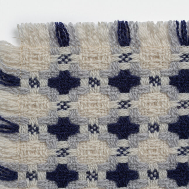 A wool table mat with a white background and blue check pattern from Japan House London.