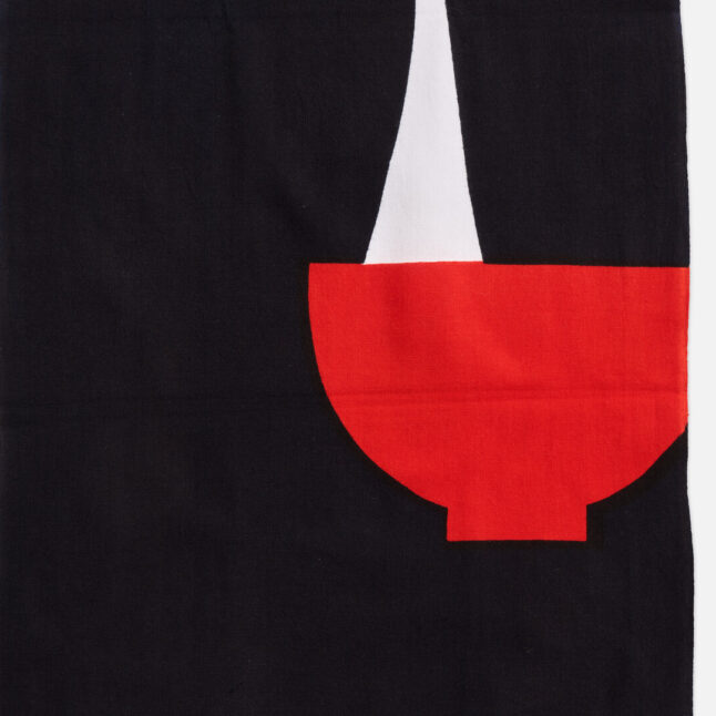 A cotton cloth with a red bowl and piece of mochi being pulled from Japan House London.