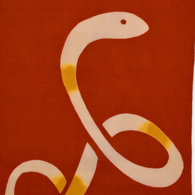A red cotton cloth with an illustration of a snake from Japan House London.