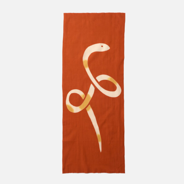 A red cotton cloth with an illustration of a snake from Japan House London.