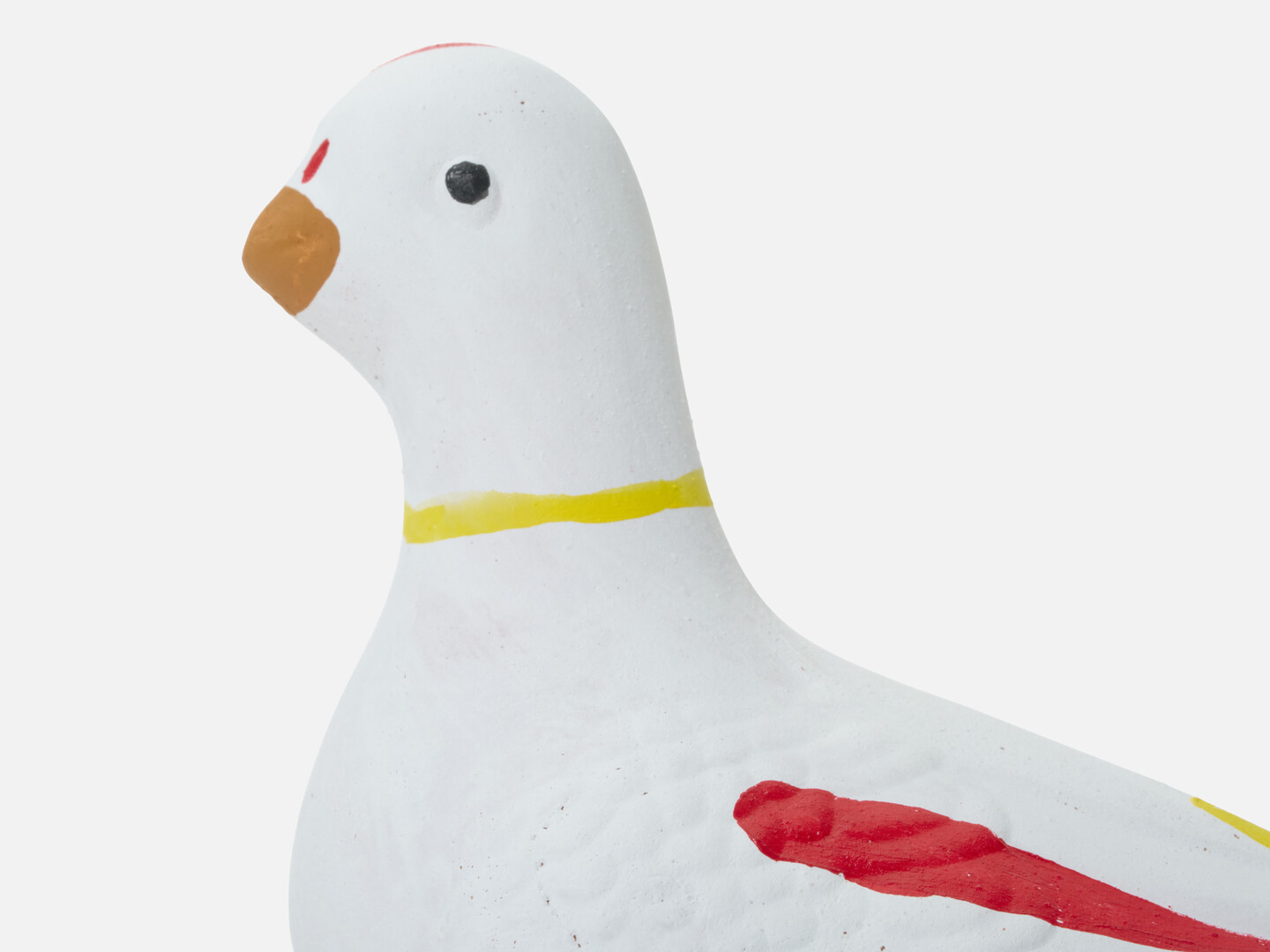 A head of a dove figurine with a yellow ring around the neck and yellow, red and blue markings from Japan House London.