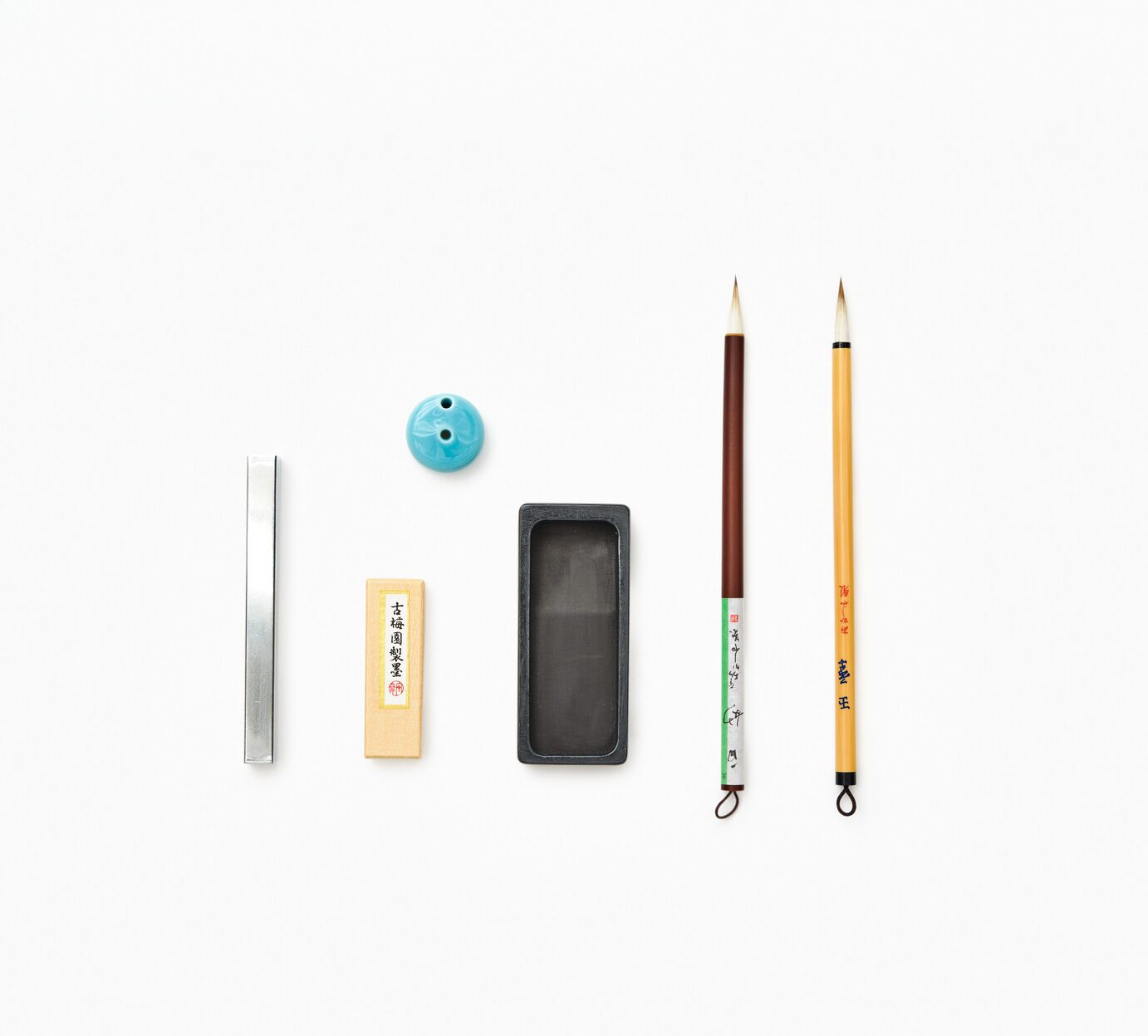 A calligraphy set of a paper weight, ink stone, a water pot, an ink grinder, two calligraphy brushes