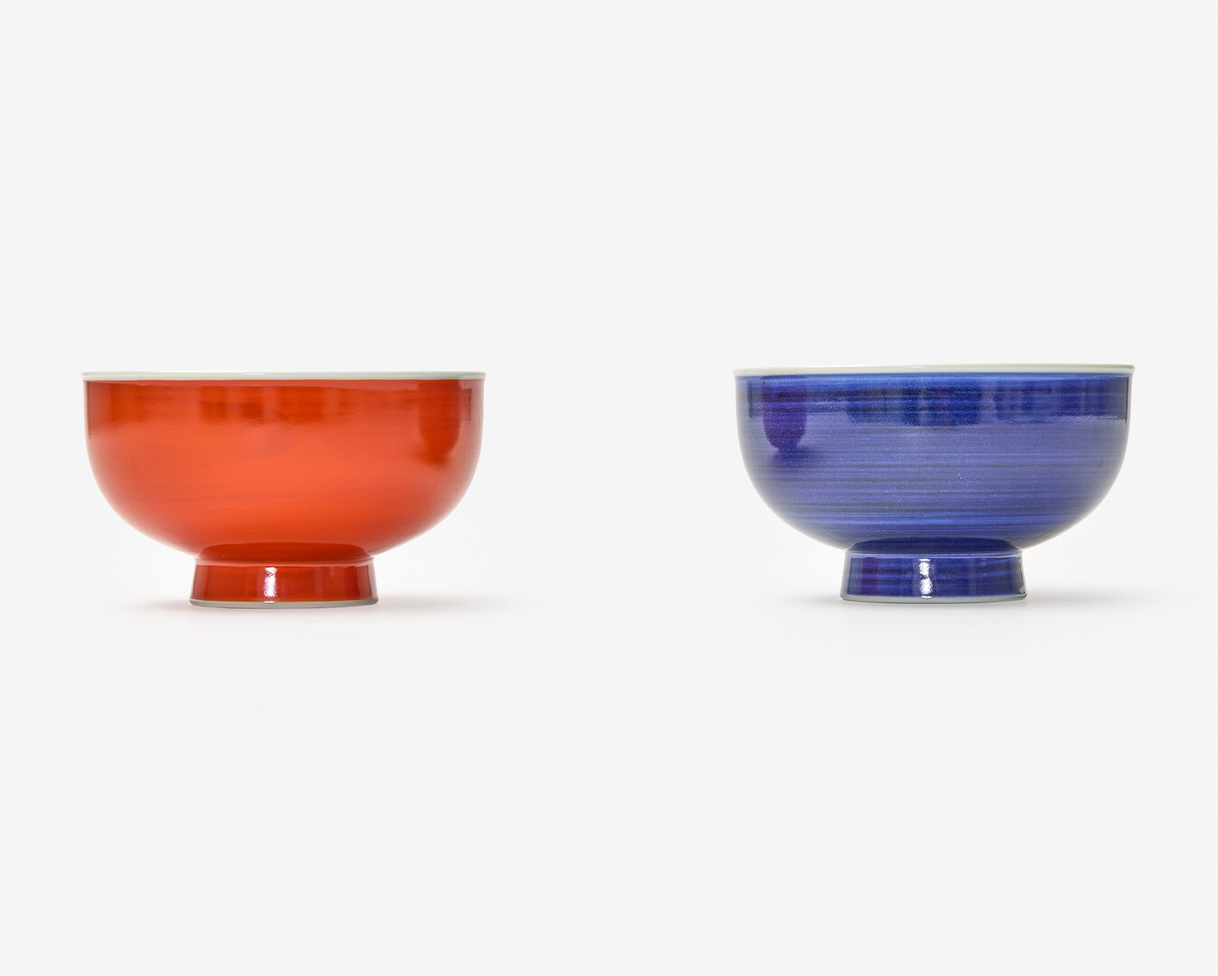 Two bowls with tall feet, one red and the other blue