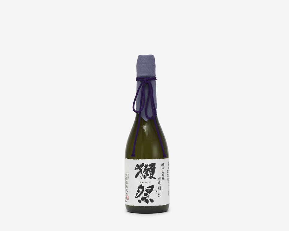 A dark brown bottle with a purple paper lid covering tied with a dark purple silk rope. The label is in Japanese with the words Dassai 23 Junmai Daiginjo