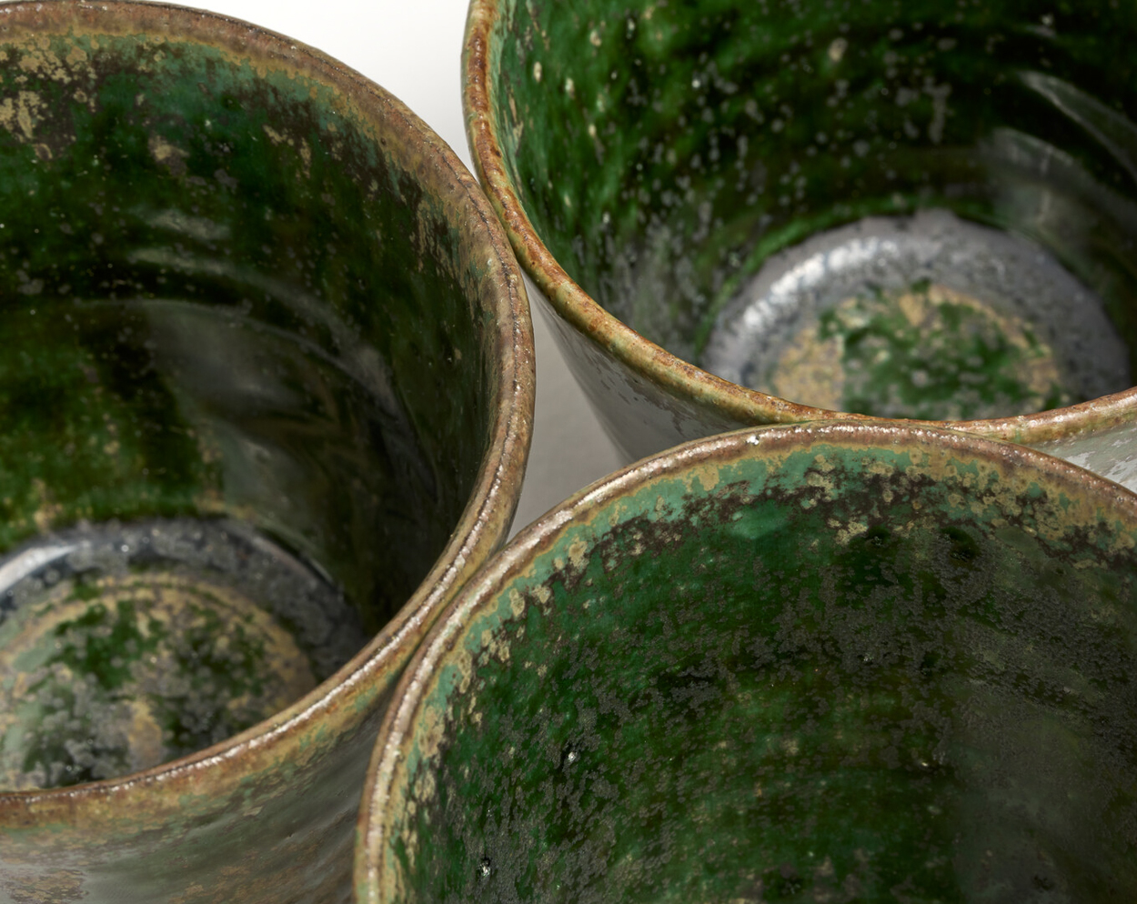 A close up of three green ceramic glasses.