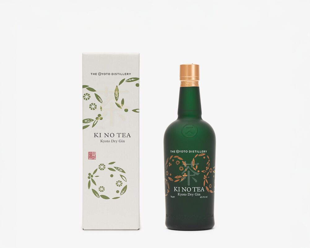 A white rectangular box with circular floral shapes across, next to it is a green bottle with the words Ki-No-Tea-Dry-Gin