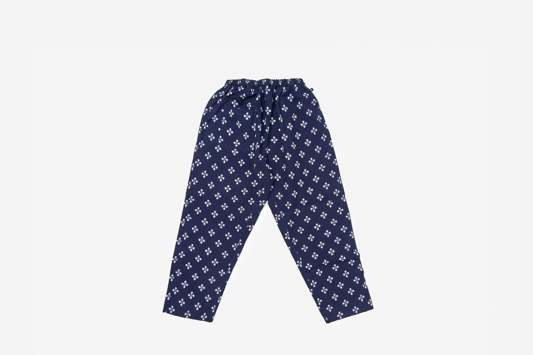 A pair of woven trousers with a repetitive white pattern over navy