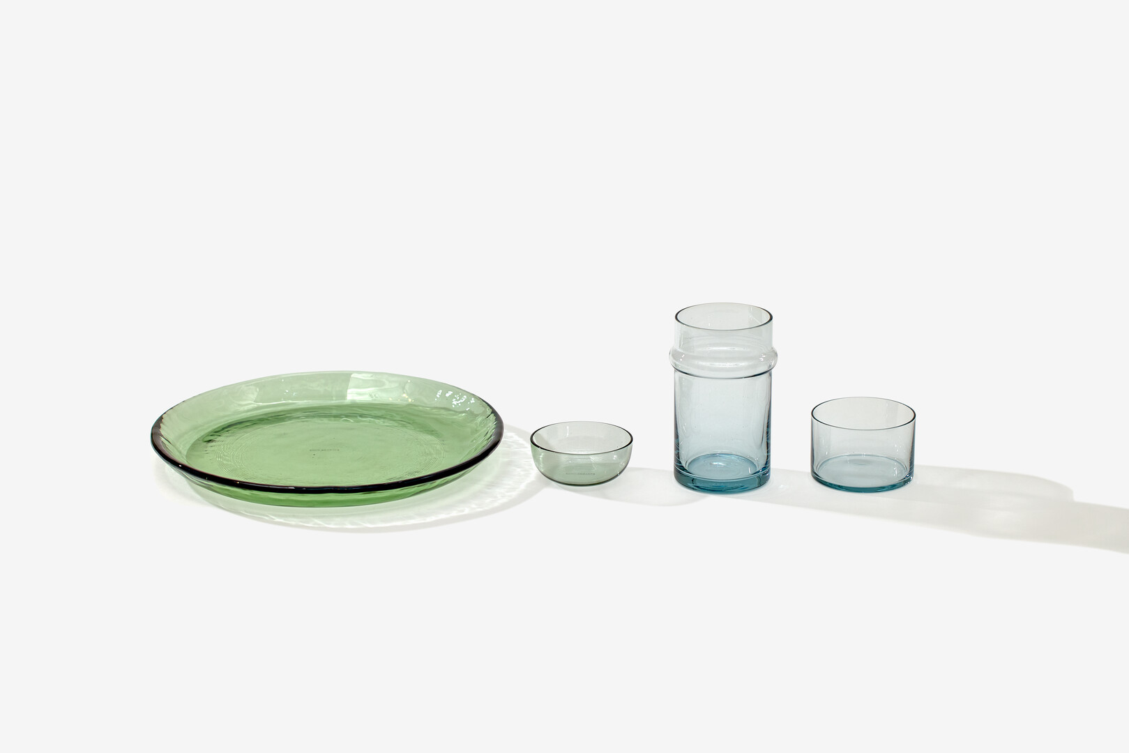 A glass plate, a small glass bowl, a small glass carafe and a small glass