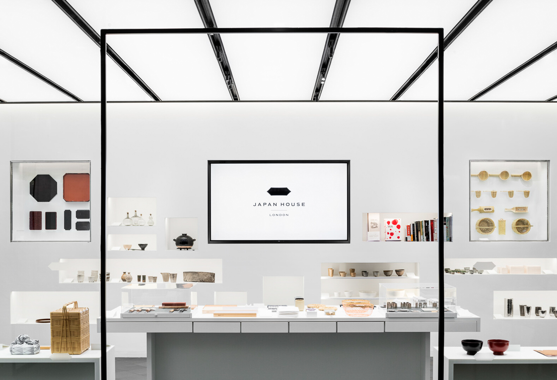 Shop interior of a white wall with alcoves housing craft products and kitchenware products on the surface in front of the wall.