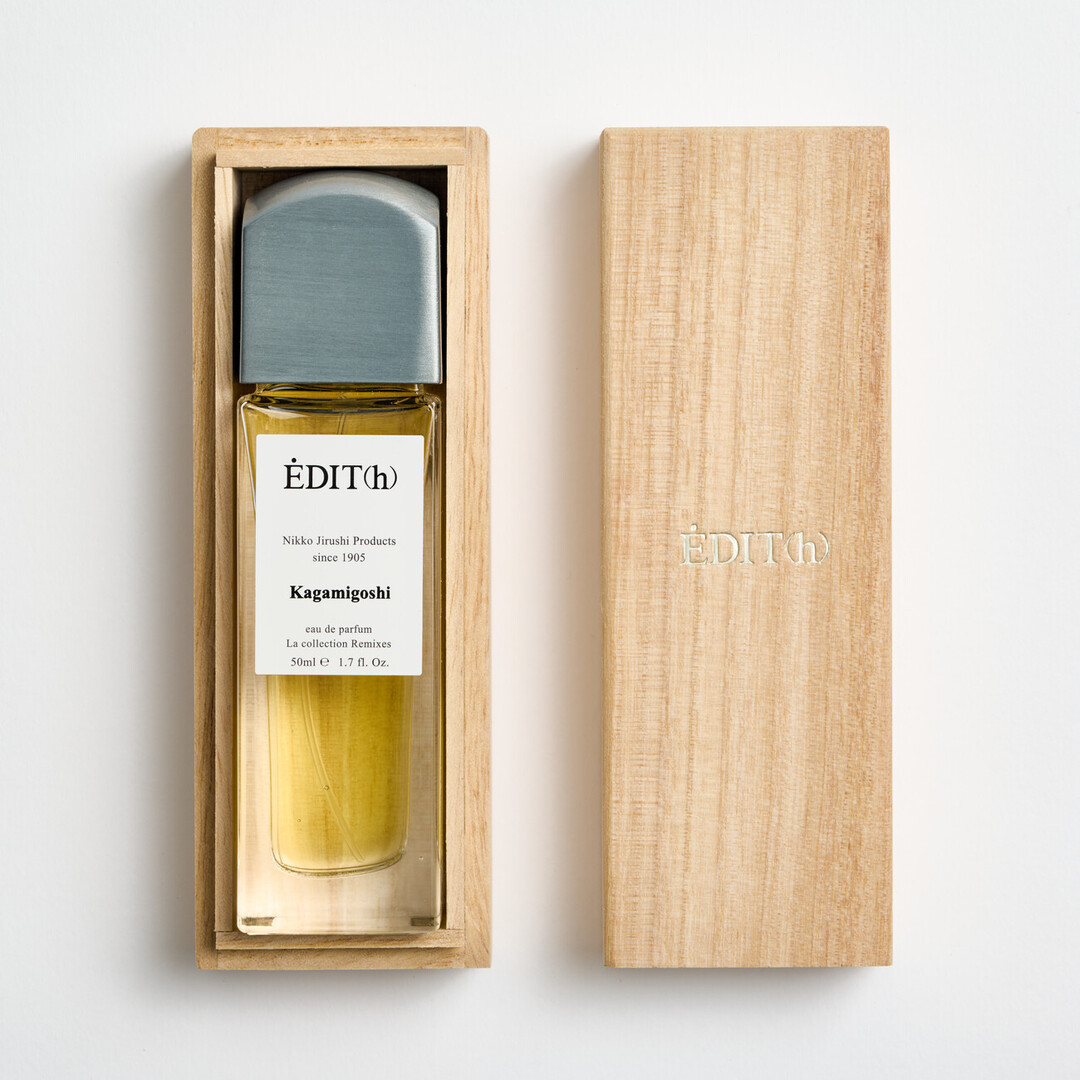 A tall rectangular perfume with a metal lid with EDIT(h) Nikko Jirushi Products since 1905 on the label in a wooden box