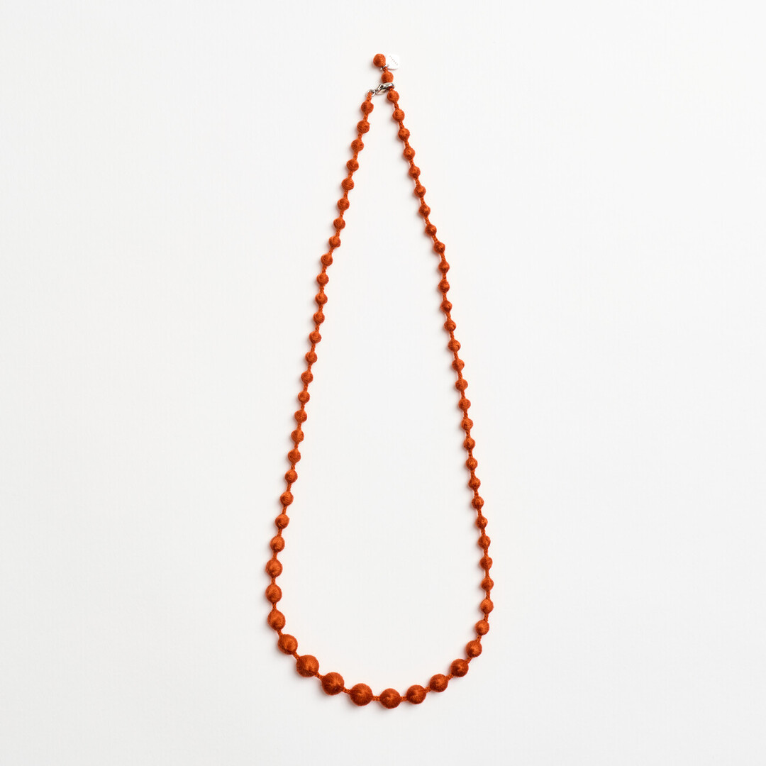 An orange textile necklace of spheres
