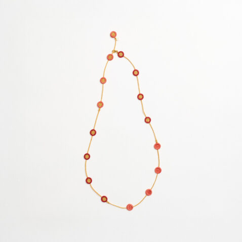 A necklace with a gold textile chain and round orange and pink flowers evenly long the chain