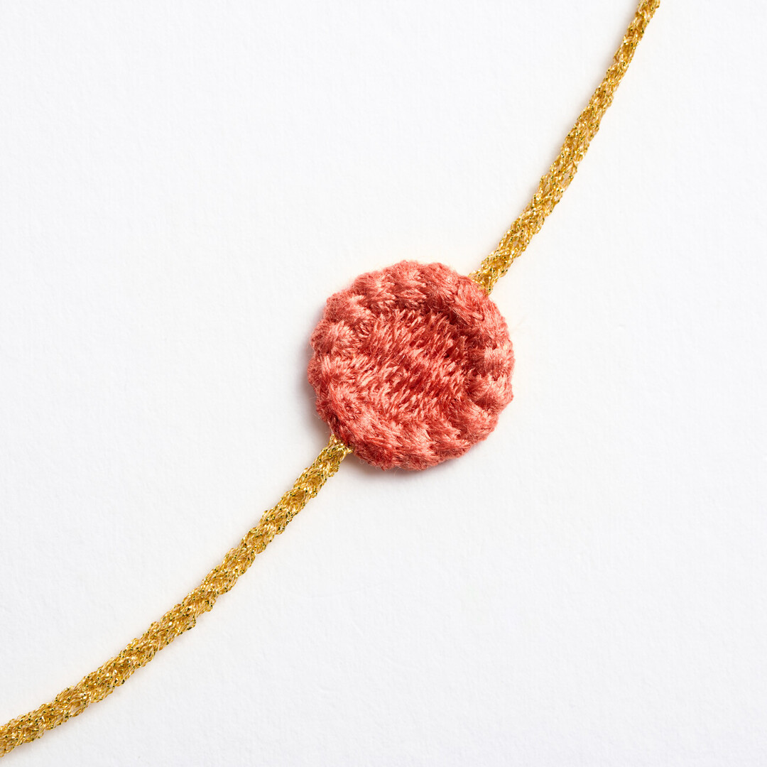 A gold textile chain with pink flower