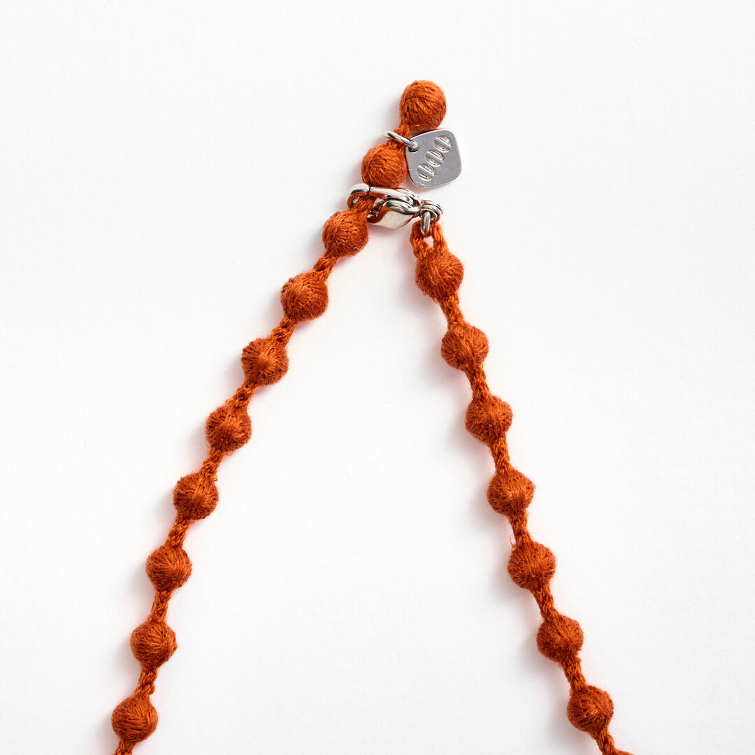 An orange textile necklace of spheres