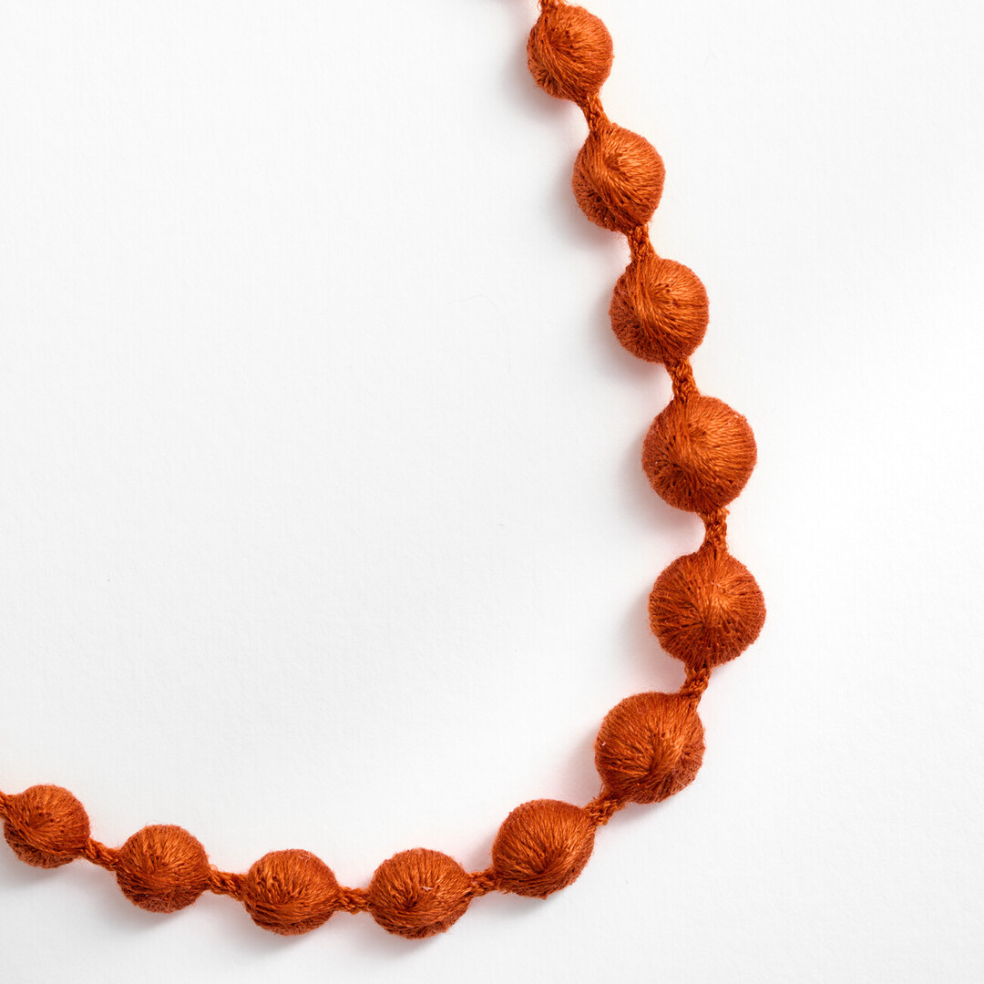 An orange textile necklace of spheres