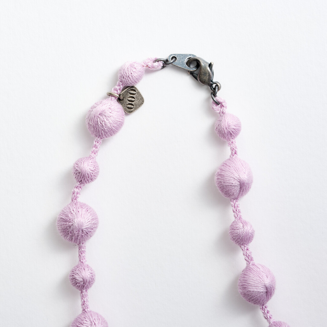 A silk lilac necklace with small and big spheres along the necklace