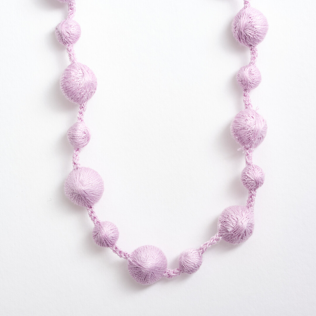 A silk lilac necklace with small and big spheres along the necklace