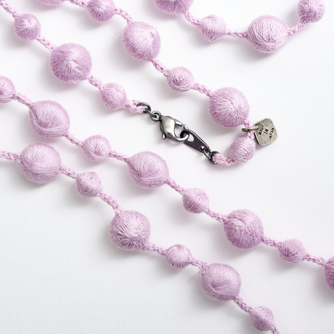 A silk lilac necklace with small and big spheres along the necklace