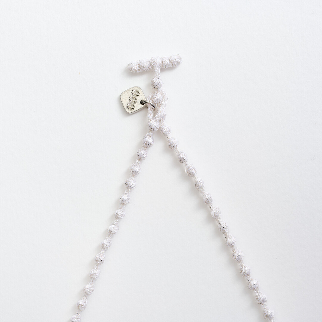 A silver textile necklace of a chain of small spheres