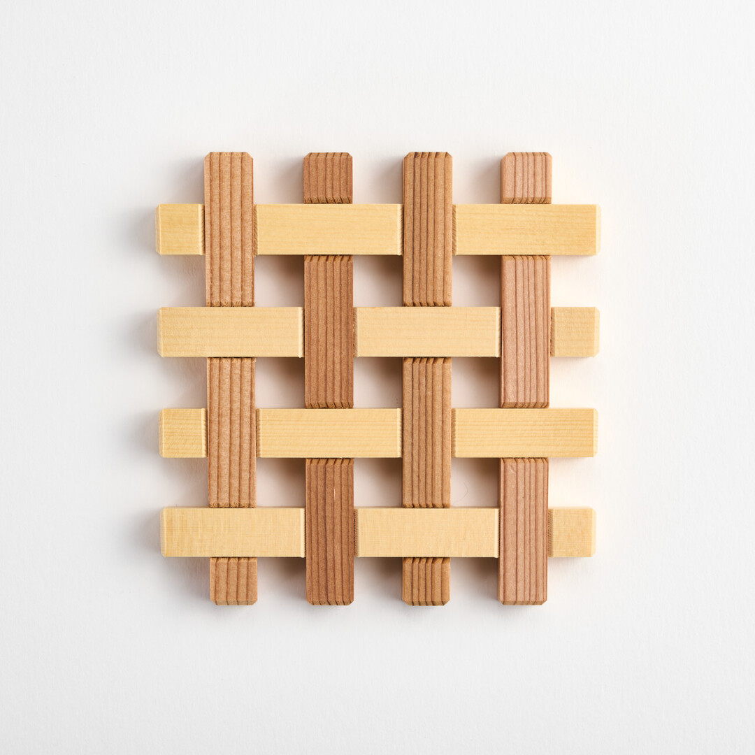 A wooden coaster with joints joining strips of wood to create a woven pattern