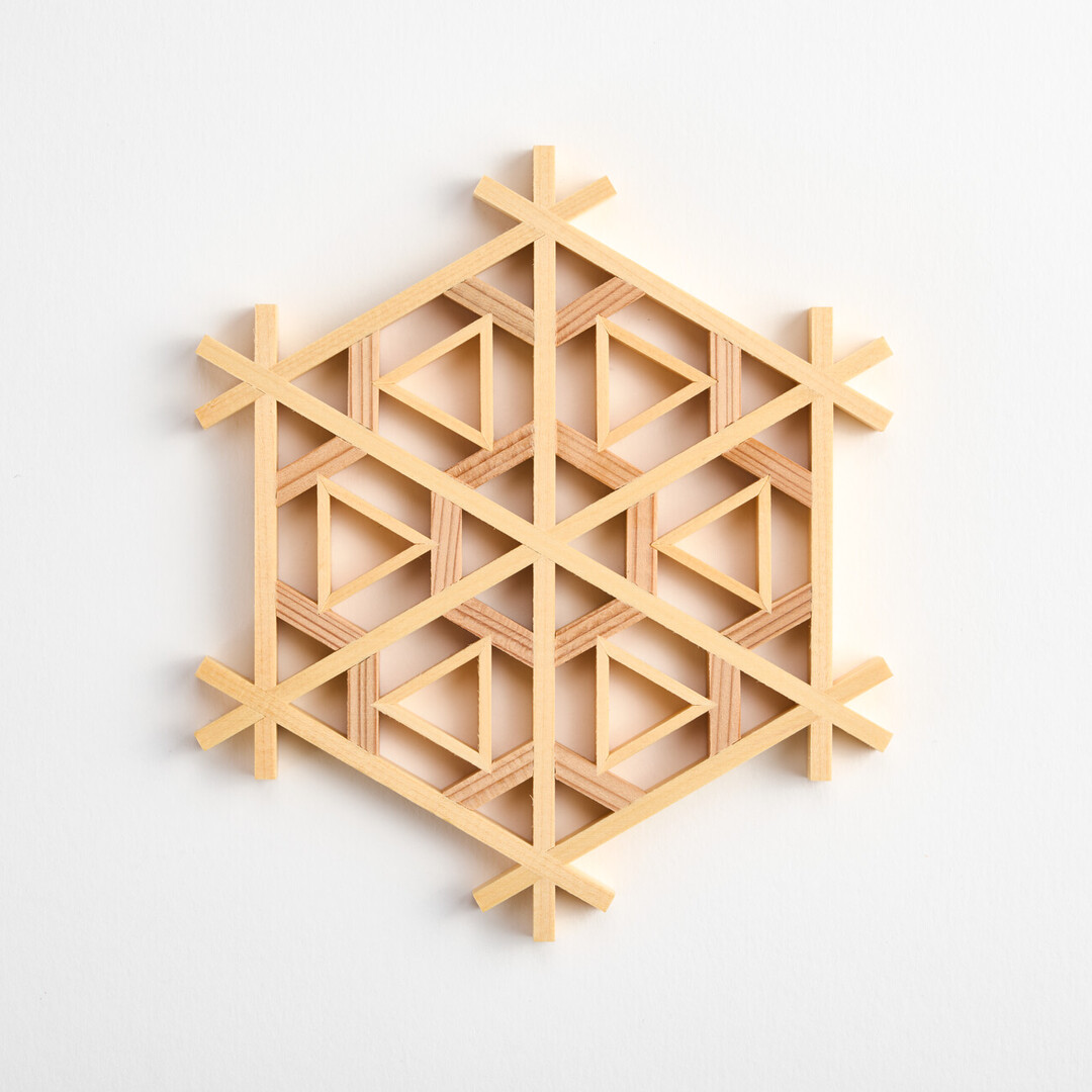 A wooden coaster made from strips of wood carefully assembled in a tortoiseshell pattern with triangles