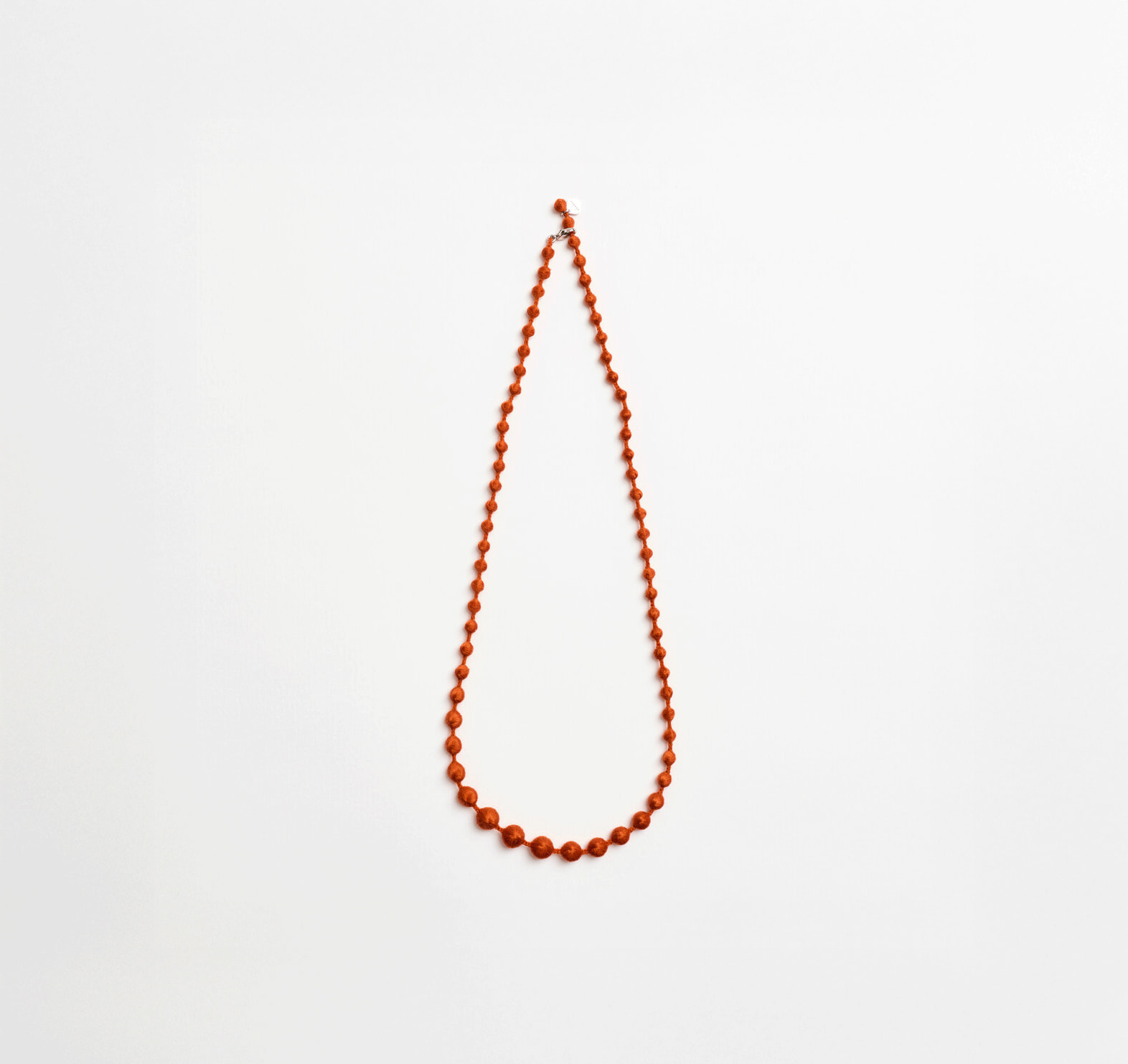 Orange necklace made with small spheres by Triple O from Japan House London.