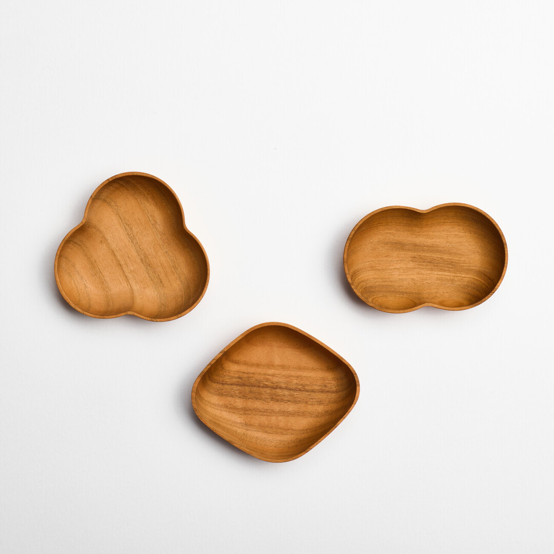 Three small handcrafted wooden plates, one shaped as a three leaved sprout, another a two leaved sprout and the other a diamond