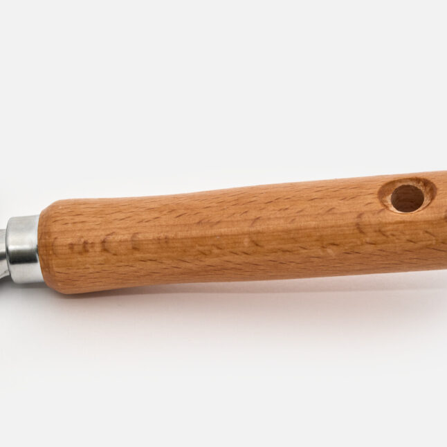 The wooden handle of a hand shovel with a hole on the end of it