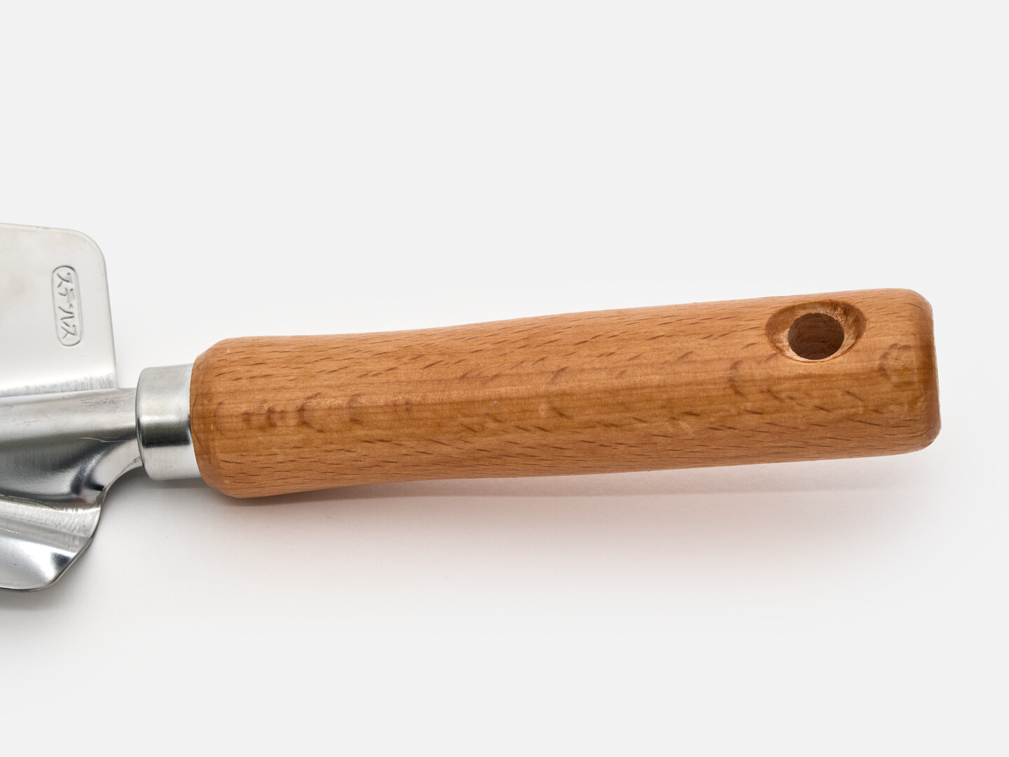 The wooden handle of a hand shovel with a hole on the end of it