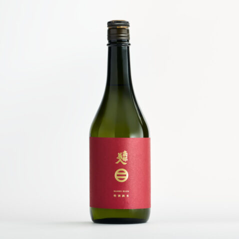 A green bottle with a red label and gold writing of Nanbubijin Sake