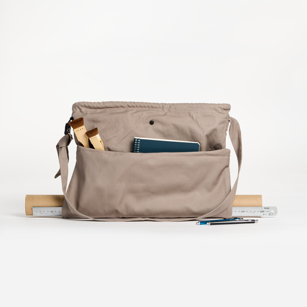 A grey tote bag with two brushes and a note book.