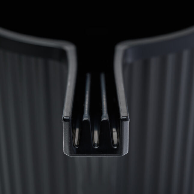 An open spout of a black watering can with two ledges running along.