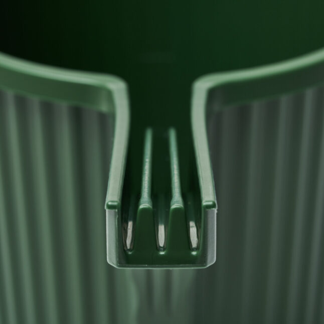 An open spout of a dark green watering can with two ledges running along.