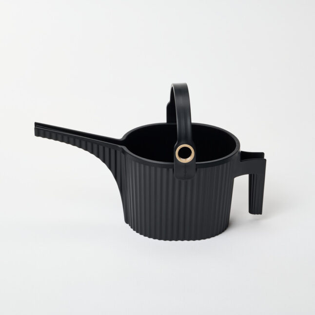 A black watering can with handle on the body and another arching over with a gold hole for the hose to fill with water.
