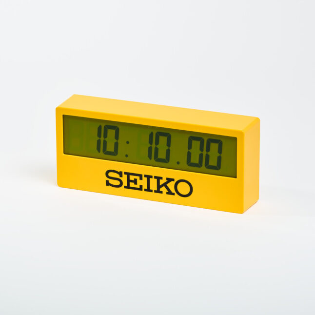 Yellow digital mantel clock with the words SEIKO under the screen in black and screen showing the time 10:10