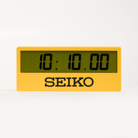 Yellow digital mantel clock with the words SEIKO under the screen in black and screen showing the time 10:10