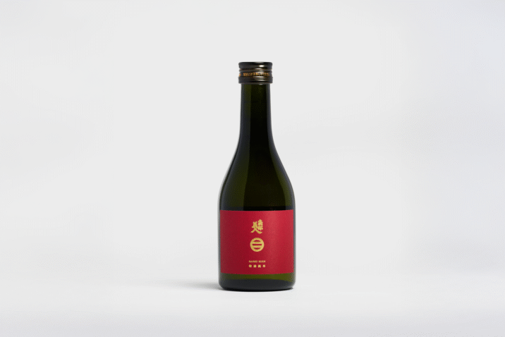 A small, dark bottle with a red label and gold words of Nanbubijin